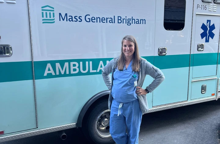 female medical provider in scrubs standing by an ambulance
